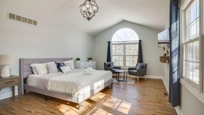 Un dormitorio con cama, candelabro, ventana y una silla.