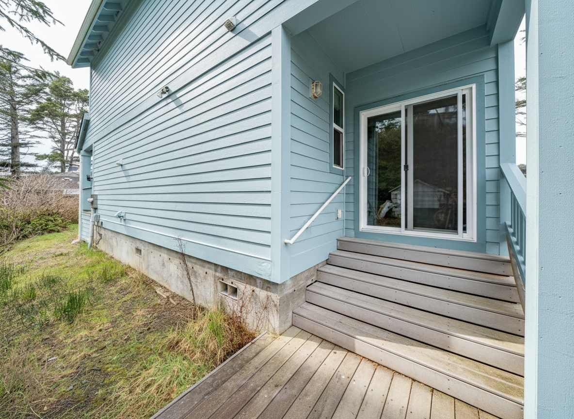 A house with a front porch, a sliding glass door, and a concrete foundation.