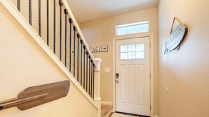 A staircase with a wooden handrail, a white door with a window, and a wall-mounted fish decoration. - Canal Cottage with Kayak Dock, Walk to Beach (Lincoln City)