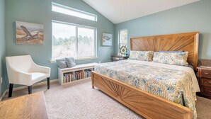 A bedroom with a bed, a chair, a bookshelf, and a window. - Canal Cottage with Kayak Dock, Walk to Beach (Lincoln City)