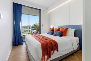 A modern bedroom with a large bed, a view of the outside, and a balcony. - 2BR Beachside Resort - 50m to the sea (Choeng Thale)