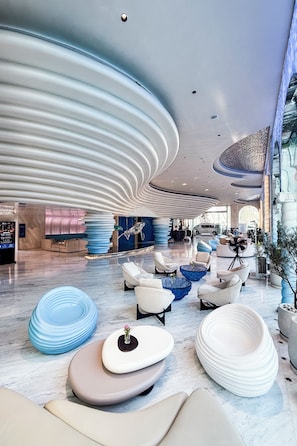 Eine moderne Lobby mit individuellem Sitzmobiliar, einer großen Glasfassade und einem markanten Deckenentwurf.