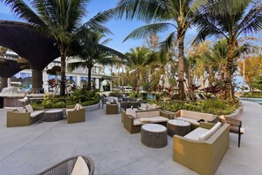 An outdoor seating area with wicker furniture, palm trees, and a pool in the background. - 2BR Beachside Resort - 50m to the sea (Choeng Thale)