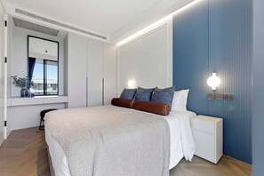 A modern bedroom with a large bed, bedside tables, a window with a view, and built-in lighting. - 2BR Beachside Resort - 50m to the sea (Choeng Thale)