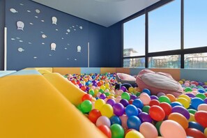 A children's play area with a ball pit and slides, large windows, and a blue wall with fish decorations. - 2BR Beachside Resort - 50m to the sea (Choeng Thale)