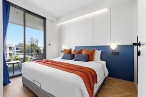 A modern hotel room with a large bed, a balcony with a view, and a bright ceiling light. - 2BR Beachside Resort - 50m to the sea (Choeng Thale)