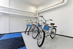 A room with white walls, a blue mat on the floor, and four bicycles with blue license plates. - 2BR Beachside Resort - 50m to the sea (Choeng Thale)