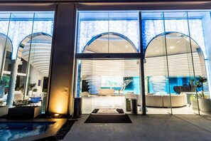 Ein moderner Hotel Eingangsbereich mit Glastüren, einer Rezeption und einem Poolbereich.