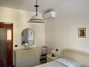 Ein Schlafzimmer mit Bett, Schminktisch, Spiegel, Lampe und Deckenventilator.