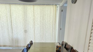 A dining room with a long table, chairs, a ceiling light, and a clock on the wall. - Waikiki  beach is just across  street. (Honolulu)