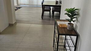 A spacious room with a dining table, chairs, a potted plant, and a ceiling fan. - Waikiki  beach is just across  street. (Honolulu)
