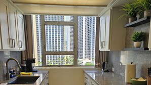 A modern kitchen with a large window, built-in cabinets, a countertop, and a stove. - Waikiki  beach is just across  street. (Honolulu)