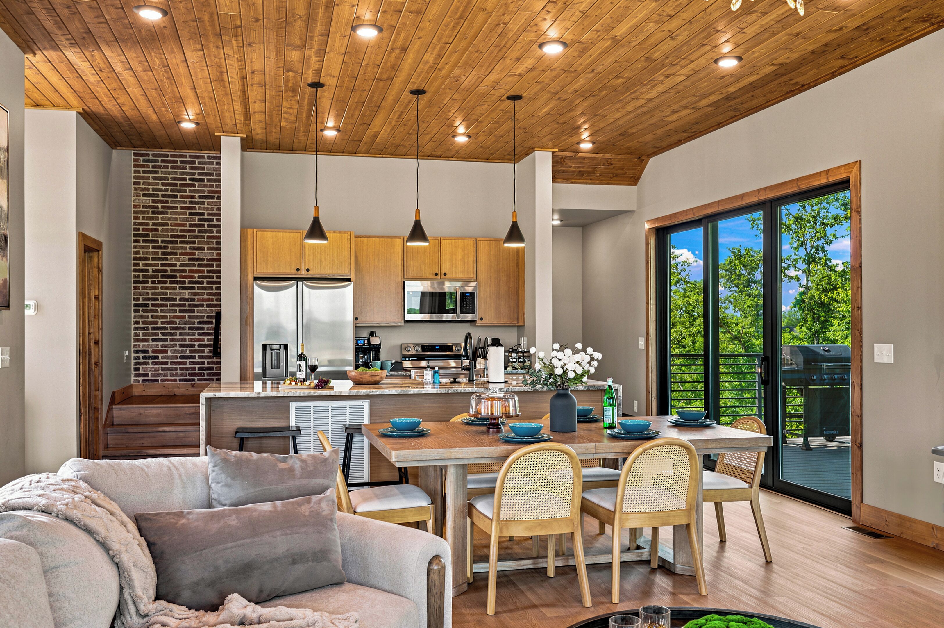 A modern kitchen with wooden cabinets, stainless steel appliances, and pendant lighting.
