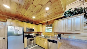 A kitchen with wooden cabinets, stainless steel appliances, and a granite countertop. - Budget friendly, Smoky Mountain Cabin Rental | Sleeps 10 | Pool Table (Pigeon Forge)