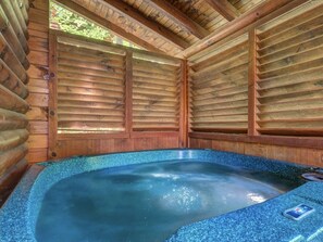 Un bain à remous dans un chalet en bois doté d’un plafond incliné et de murs en bois.