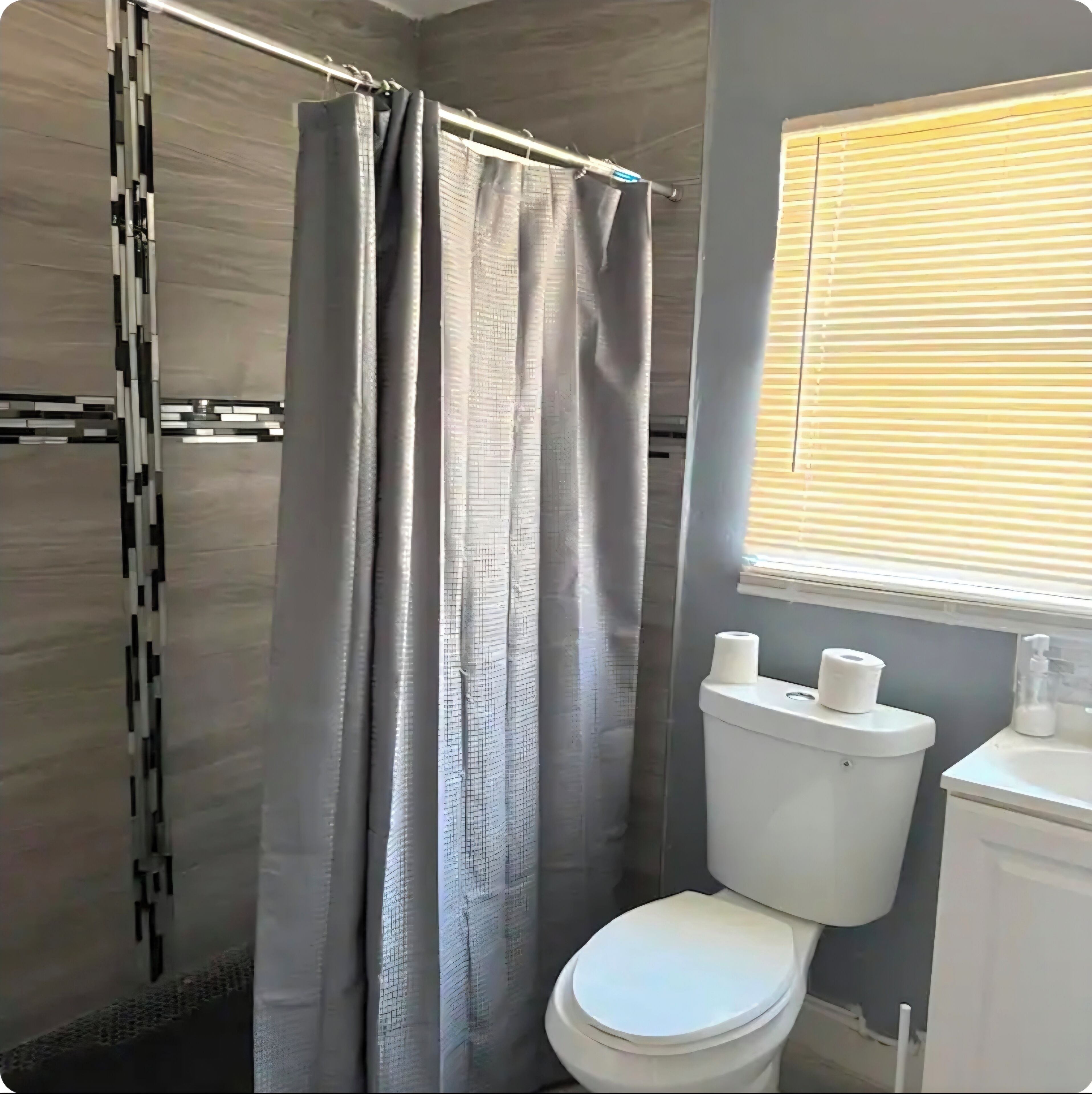 Un baño con cortina de ducha, inodoro y persianas.