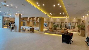 Eine großzügige Lobby mit Sitzbereichen, einem Empfangstresen und einem großen Fenster.