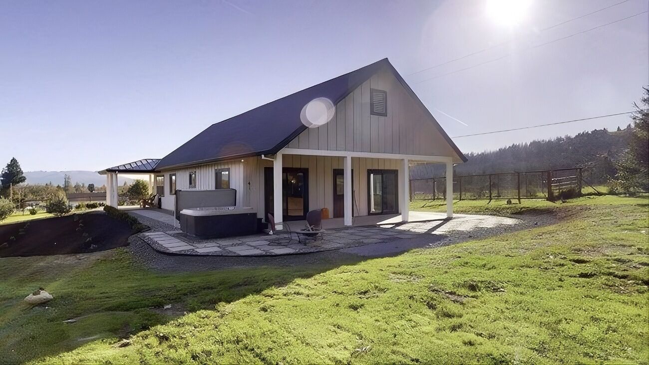 Uma casa com varanda coberta, um espaço de pátio e vista para uma paisagem montanhosa.