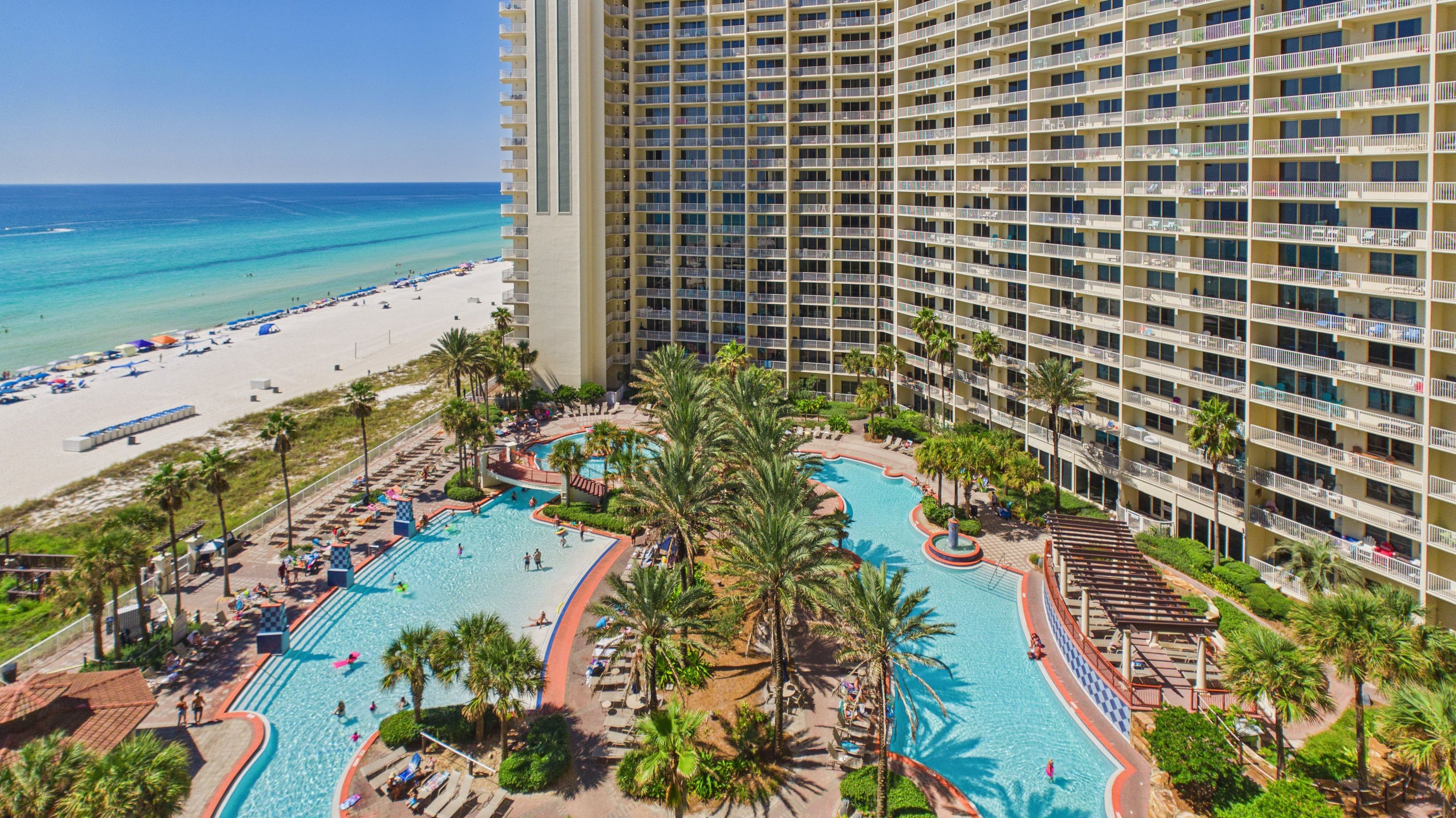 Un resort con una amplia zona de piscina, playa y un edificio de gran altura.