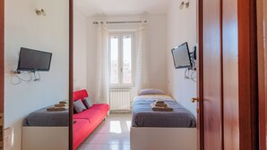 Ein Hotelzimmer mit zwei Betten, einem Fernseher und einem Fenster.