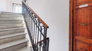 Eine Marmortreppe mit schwarzem schmiedeeisernen Geländer, das zu einer Holztür mit Messingknauf führt.