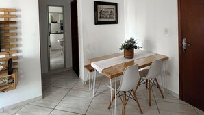 En matplats med ett träbord, vita stolar, en krukväxt och en inramad tavla på väggen.
