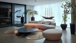 Een moderne woonkamer met een bank, een rond salontafeltje en potplanten.
