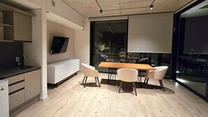 Een moderne keuken met een inbouwkoelkast, een eethoek met een houten tafel en vier stoelen, en een groot raam met uitzicht.