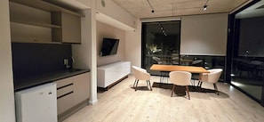 A modern kitchen with a built-in refrigerator, a dining area with a wooden table and four chairs, and a large window providing a view of the outside.