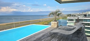 A rooftop pool with a view of the sea and a road.