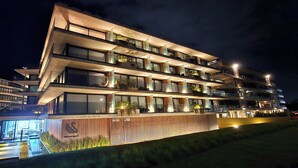 Een hotel met meerdere verdiepingen, balkons, grote ramen en een goed verlichte gevel.