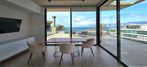 Una habitación moderna con un ventanal grande, una mesa de madera y cuatro sillas.