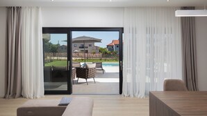 Een moderne woonkamer met een grote schuifdeur die leidt naar een terras.