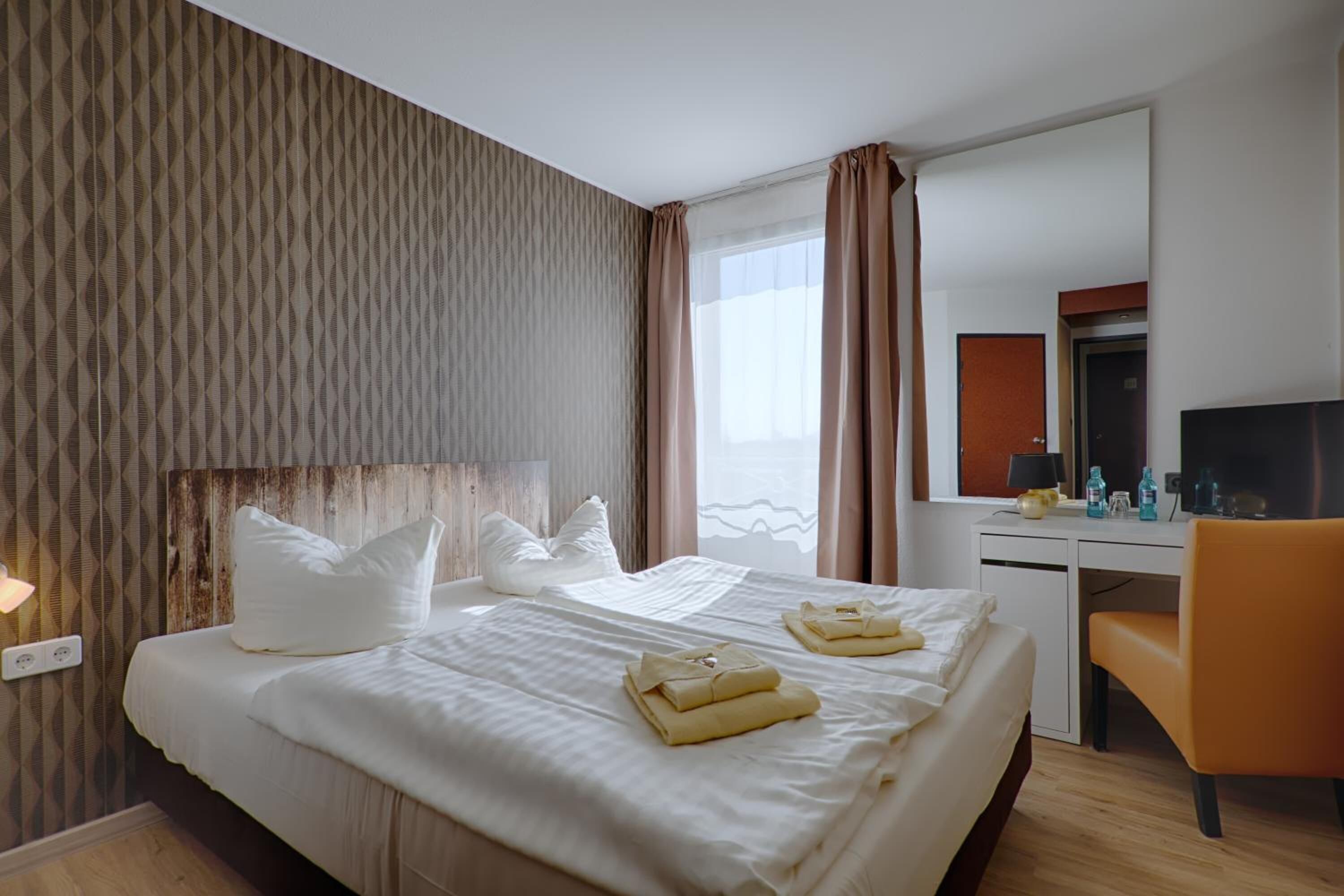 Una habitación de hotel con una cama, un escritorio, una silla y un televisor.