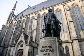 Johann Sebastian Bachin patsas historiallisesti merkittävän rakennuksen edessä, ja rakennuksen arkkitehtuuri edustaa goottilaista tyyliä.