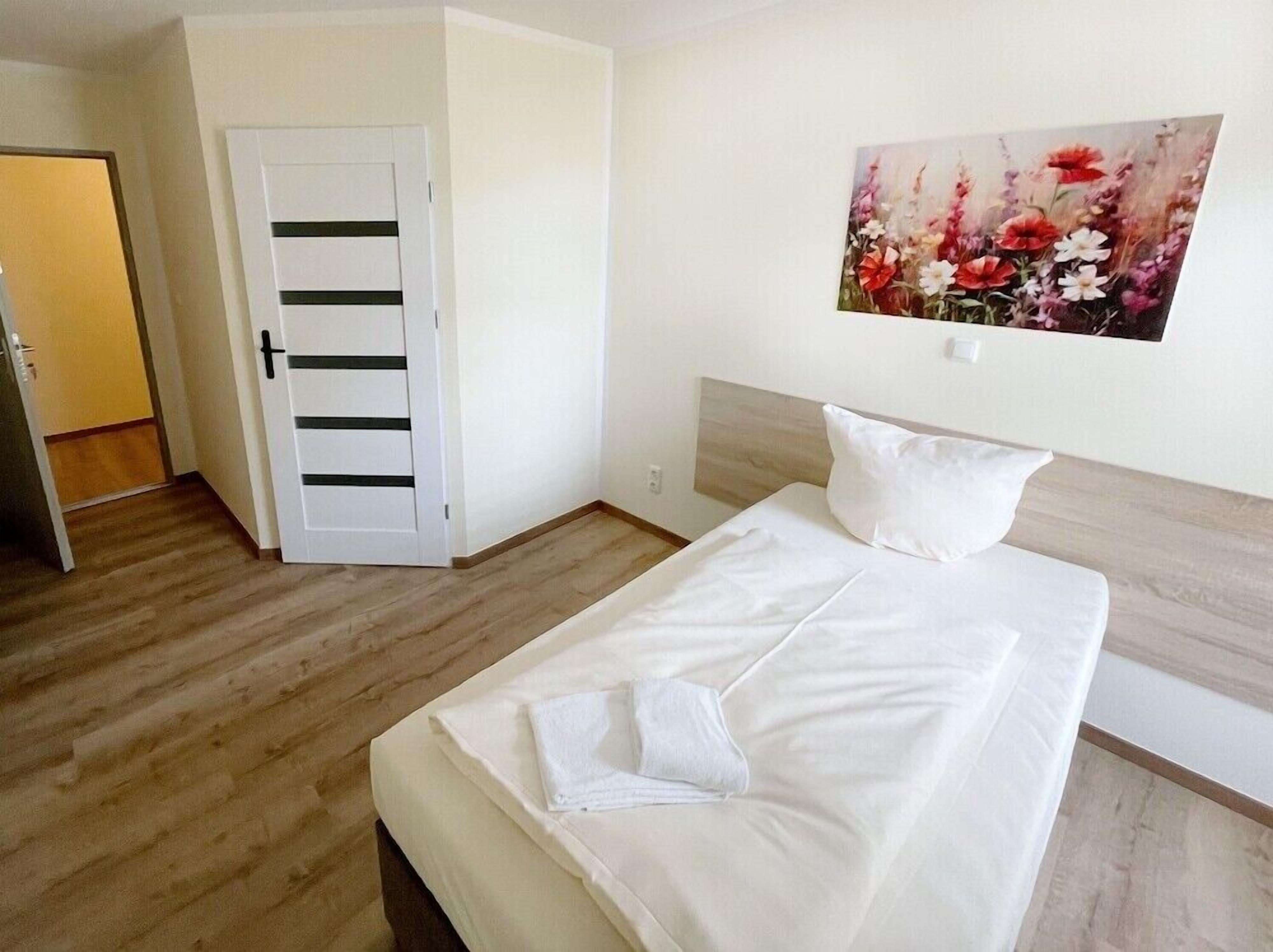 Ein Hotelzimmer mit einem Bett, einem Blumenbild und einer Tür.