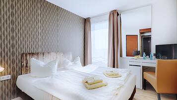 Ein Hotelzimmer mit einem großen Bett, einem Schreibtisch, einem Sessel und einem Fernseher.
