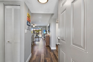 A hallway with a wooden floor, white doors, and a ceiling fan. - New to Rental Program! OVC E26, 2/2 Near Pool & Ocean! (St. Augustine)