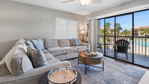 A modern living room with a sectional sofa, a round coffee table, and a ceiling fan.