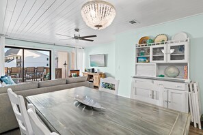Ein modernes Wohnzimmer mit Esstisch aus Holz, einer Couch, einem Fernseher und einer Chandelier.