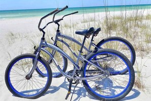 Ein Fahrrad mit '30 Avacay'-Branding auf dem Rahmen, geparkt an einem sandigen Strand mit Blick auf den Ozean.