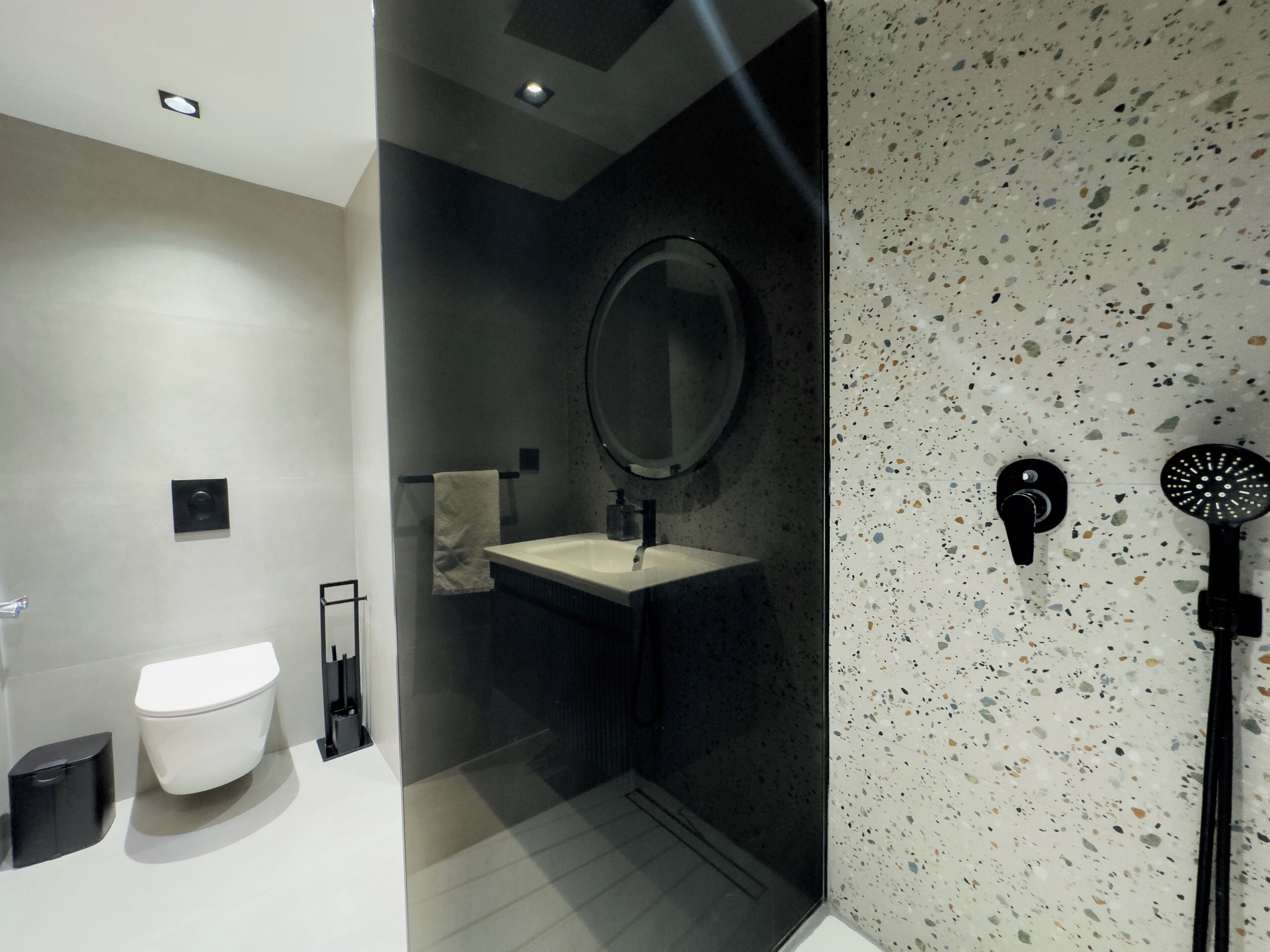 A modern bathroom with a toilet, sink, mirror, and shower.