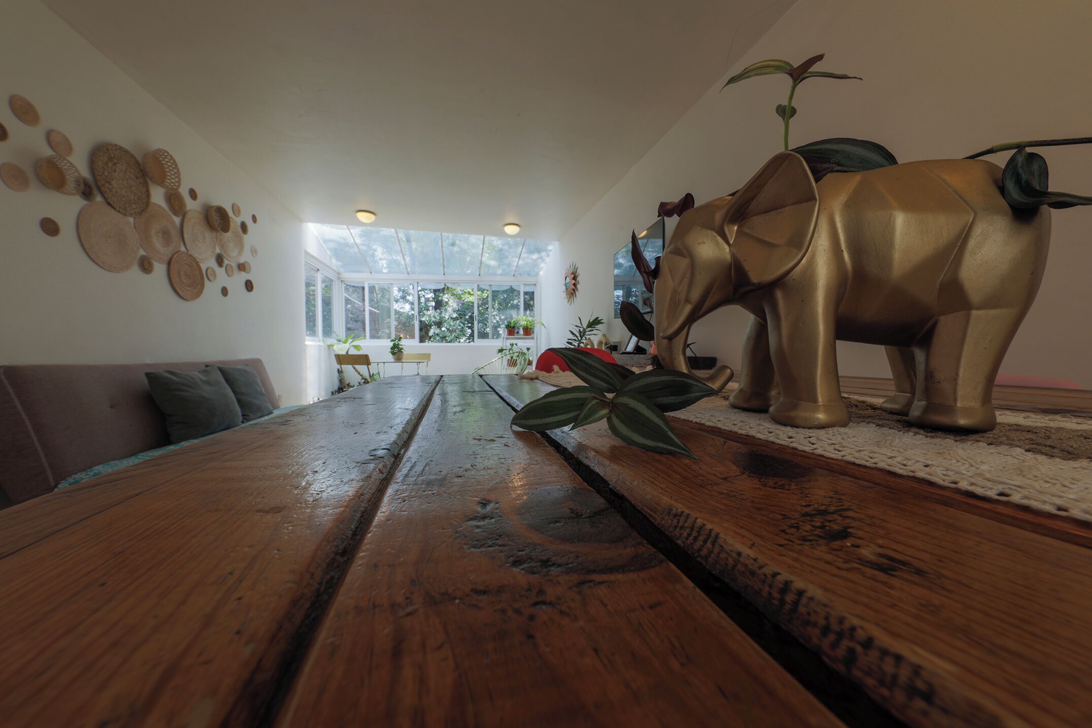 A wooden dining table with a central island, a large elephant sculpture, and a wall with circular wall decor.