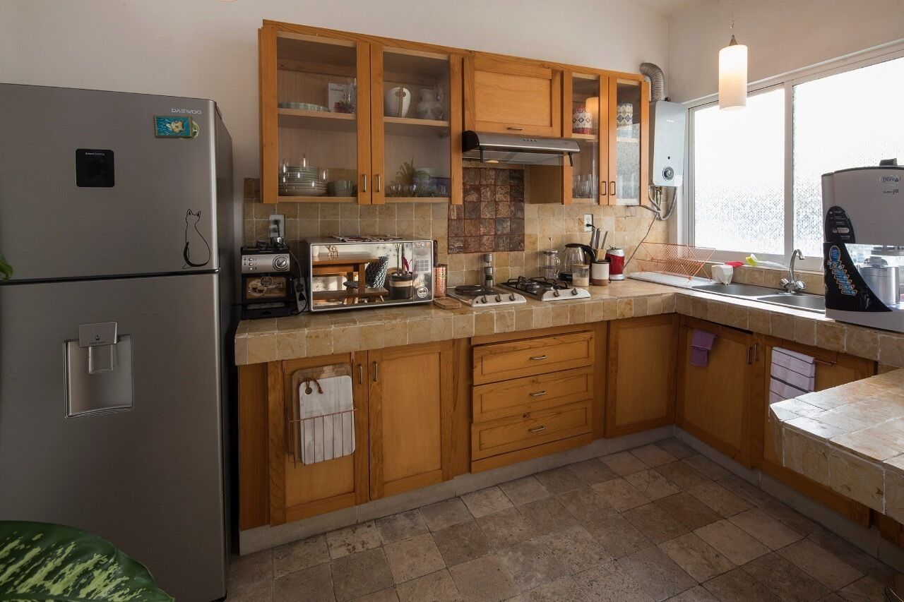 A kitchen with wooden cabinets, a stainless steel refrigerator, a gas stove, and a window providing natural light.