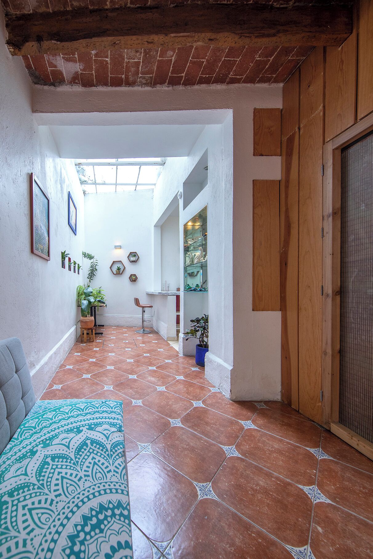 A spacious hallway with a tiled floor, a wooden door, and a glass display case.