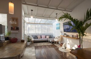 Un salon moderne avec un canapé, des fauteuils, un téléviseur et une grande plante.