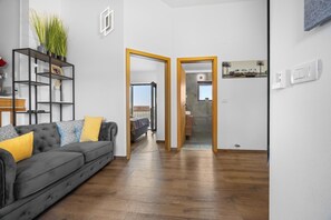 Ein modernes Wohnzimmer mit grauem Sofa, Holzboden und Blick ins Freie.
