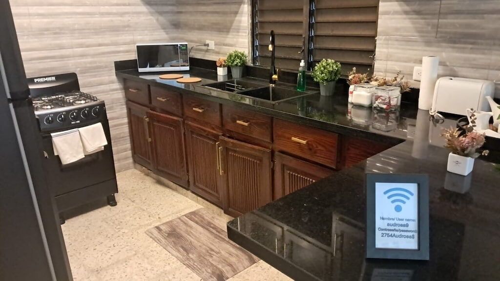 Cozinha moderna com fogão a gás, armários de madeira, bancada preta e pia embutida.