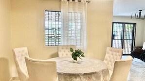 A dining area with a round table, four chairs, a potted plant, and a window with a metal grid. - Una Casita Acogedora en Tenares (Tenares)