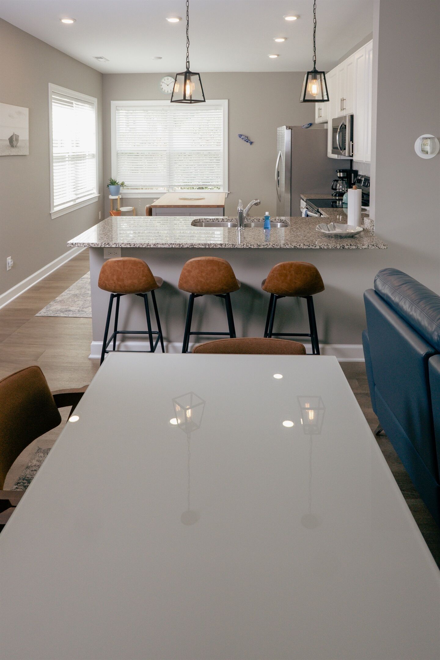 Une cuisine moderne avec un îlot central, des tabourets de bar, une table à manger et un canapé bleu.